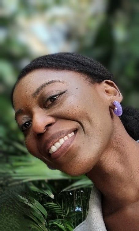 smiling black African woman in-front of out of focus palm leaves 